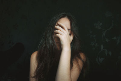 Sad young woman against black background