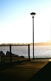 Street light on pier by sea against clear sky