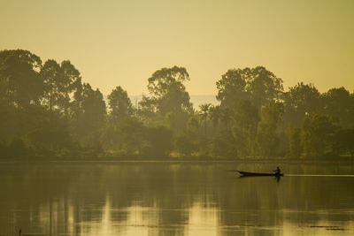 Silhouette trees by lake against sky