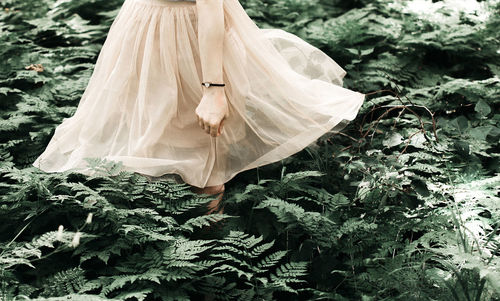 Midsection of woman standing amidst plants in forest