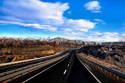 Empty road along landscape against sky