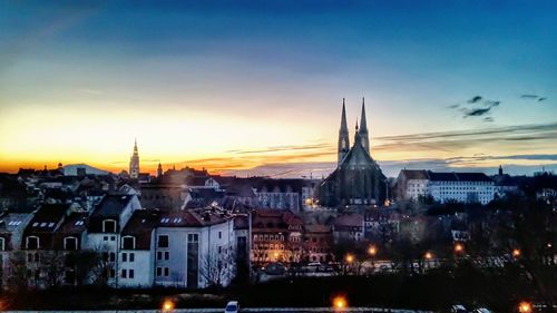 Illuminated cityscape against sky at sunset