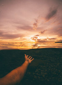 Shadow of hand on sea during sunset