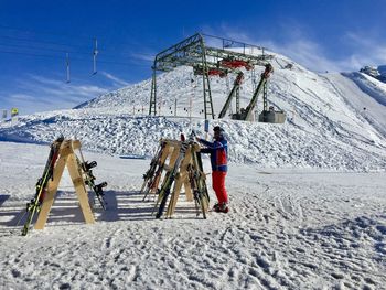 Full length of man standing by ski rack on snow