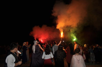 People standing against distress flare and smoke at night