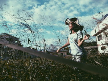 Low angle view of boy standing on field against sky