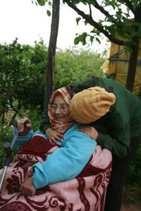 Woman kissing smiling grandmother at yard