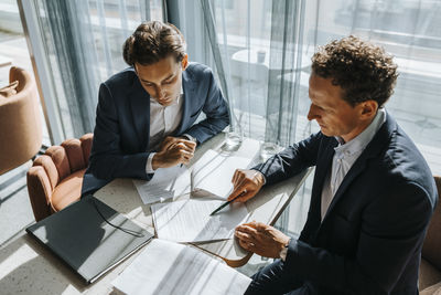 High angle view of businessman explaining contract to client at office
