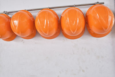 Close up hard hats hanging on hook against the dirty white wall.