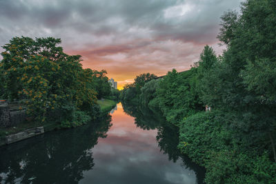 Reflection of trees on water against sky during sunset
