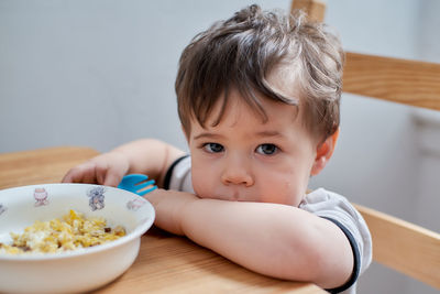 Little boy is eating eggs for breakfast and fooling around making faces