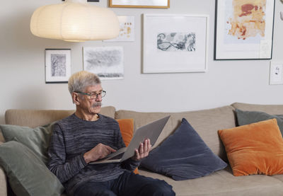 Senior man using laptop on sofa