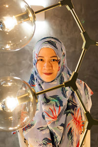 Portrait of mid adult woman wearing hijab with illuminated lighting equipment in foreground