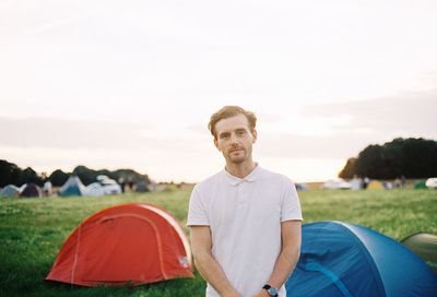 Portrait of man standing on camping field against sky