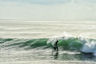 Man surfing in sea against sky