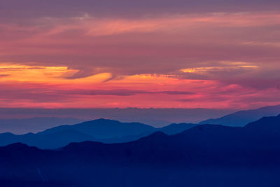 Scenic view of silhouette mountains against orange sky