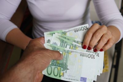 Midsection of businesswoman receiving money from man