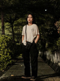 Portrait of teenage girl standing against trees