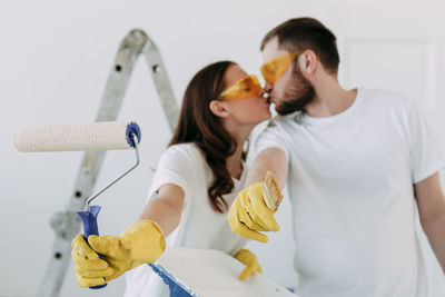 Happy smiling married couple engaged in renovation repair in the room of the house preparing to move