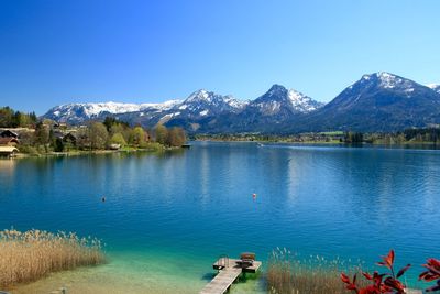 Scenic view of lake and mountains against blue sky