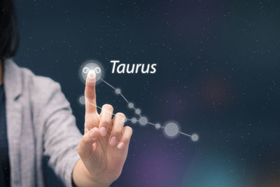 Midsection of woman touching astrology sign on digital display