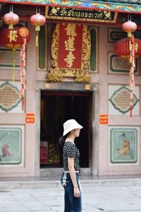 Side view of woman standing against of temple