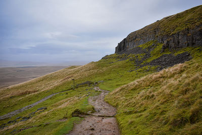 Rear view of man walking on mountain against sky