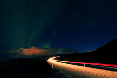 Light trails on road against sky at night