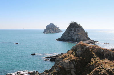 Scenic view of rock formation in sea against clear sky