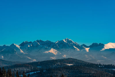 Scenic view of snowcapped mountains against clear blue sky