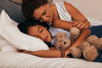 High angle view of mother and daughter lying on bed at home