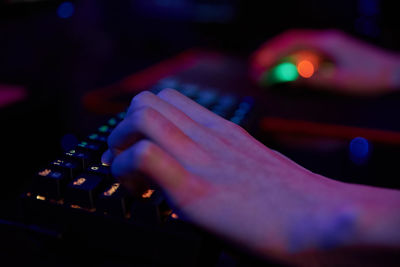 Gamer play computer game, use rgb neon colored keyboard