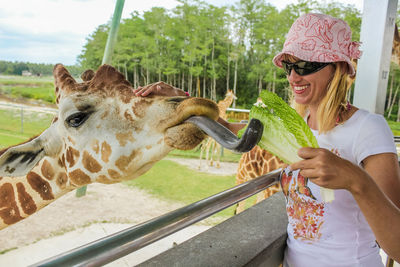 Smiling young woman with feeding giraffe