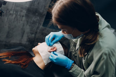 Woman piercing ear of customer