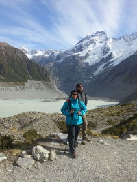 Couple standing on field against snowcapped mountains