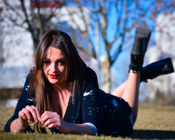 Portrait of young woman lying on field at park