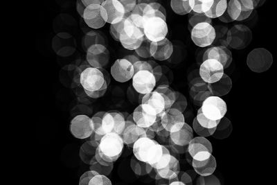 Defocused image of illuminated lights against black background