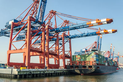 Cranes at commercial dock against clear sky