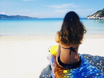 Rear view of woman swimming in sea against sky