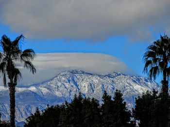 Scenic view of snow covered mountains against cloudy sky