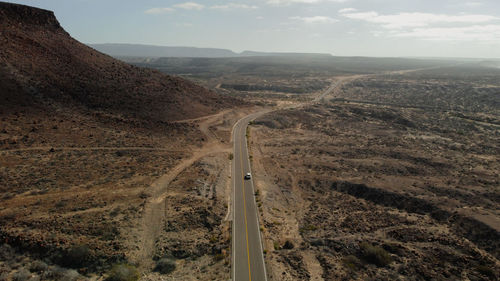 Aerial view of desert landscape against sky with a car driving on a highway in baja california sur.