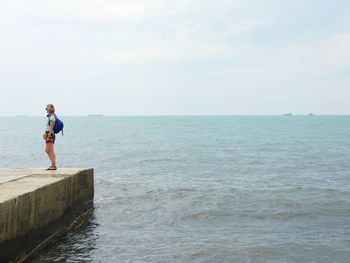 Girl looking at sea against sky