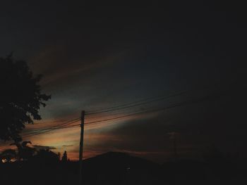 Low angle view of silhouette electricity pylon against sky during sunset