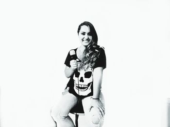 Portrait of a young woman drinking glass against white background