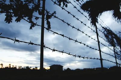 Low angle view of silhouette fence against sky