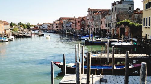 Boats moored in canal against buildings in city