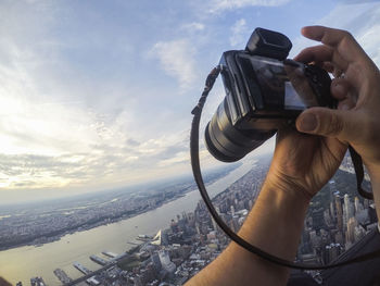 Cropped image of man photographing manhattan from helicopter against sky