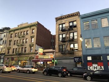 Cars on street by buildings against sky in city