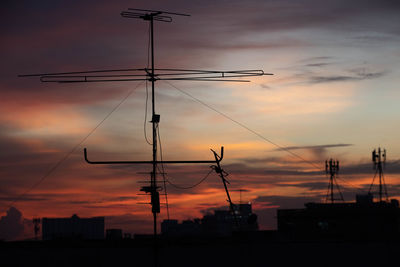 Low angle view of silhouette telephone pole against sky during sunset