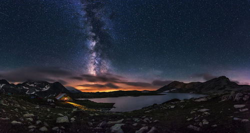 Scenic view of lake by mountains against star field